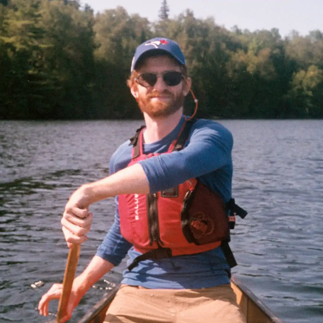 The website's author wearing sunglasses a blue hat and shirt a red life jacket.