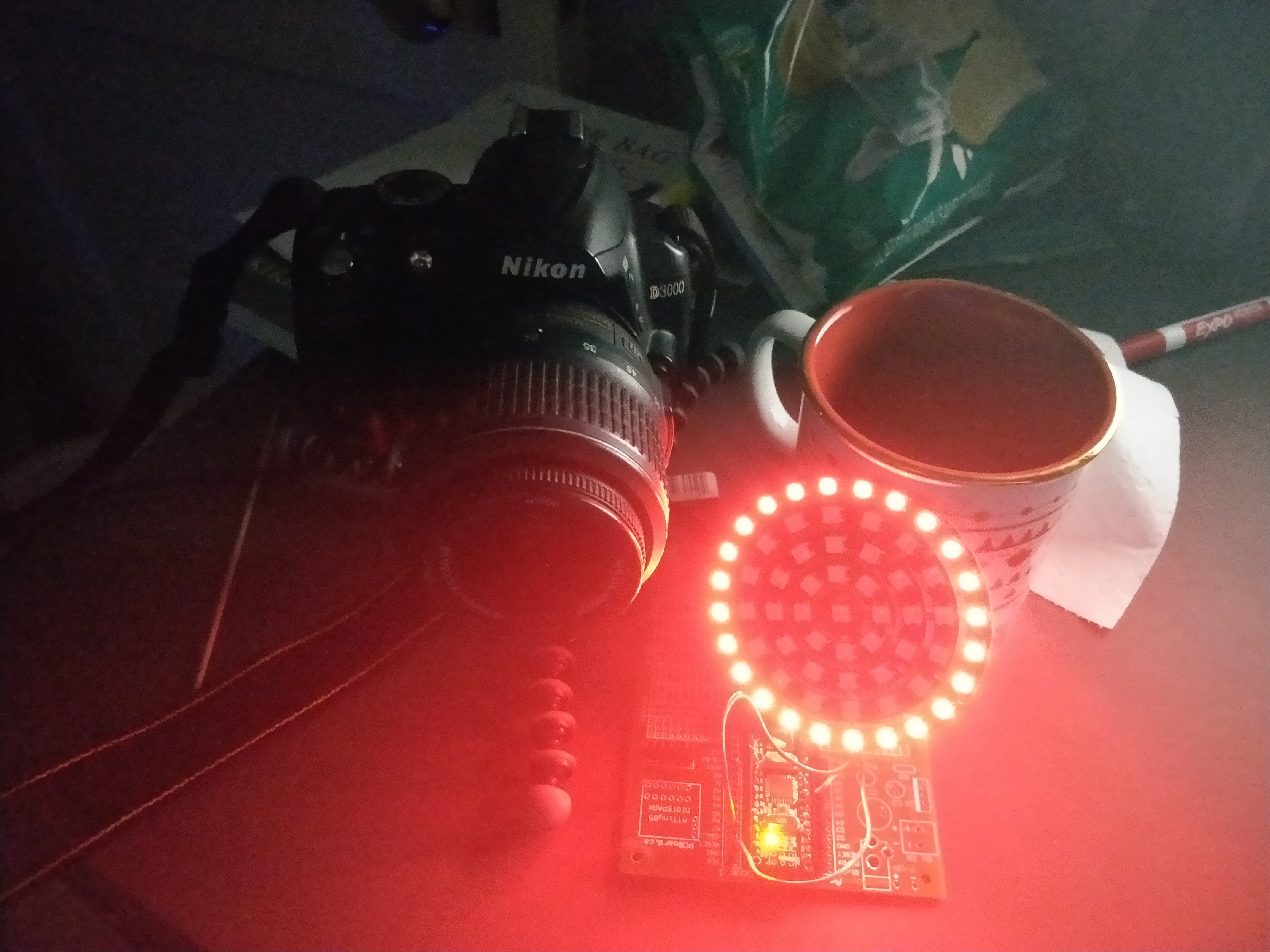 A picture of A Nikon SLR camera next a ring of LEDs. The ring is illuminated bright red.